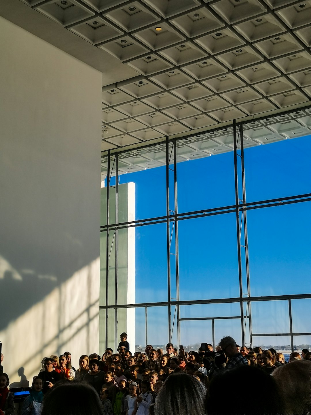 Diverse group gathers in a spacious room with large windows.