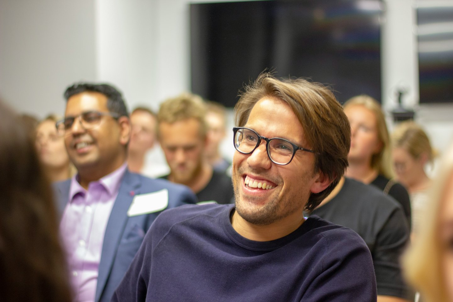 Man in glasses smiles at a business conference.